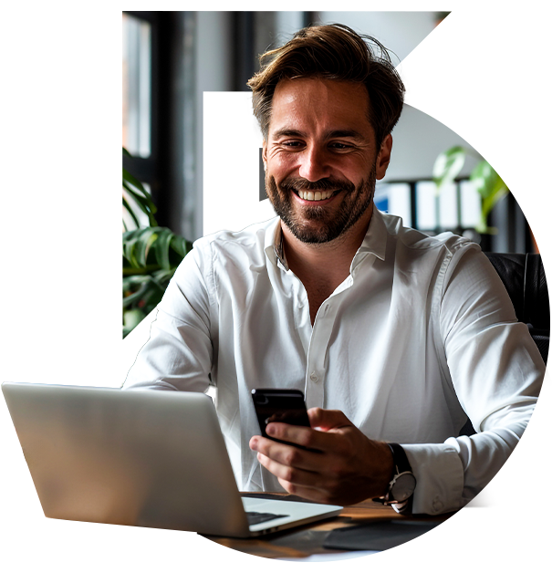 homem sorrindo usando smarphone e laptop